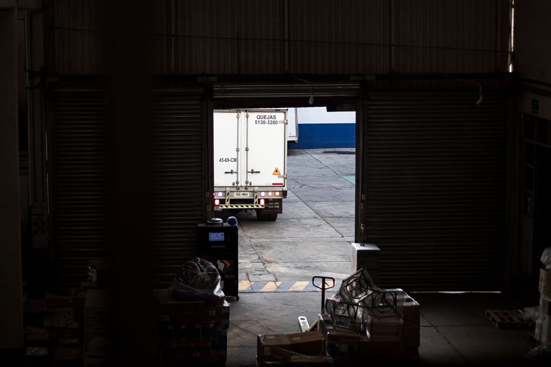 Warehouse interior with a roller door open and truck visible beyond