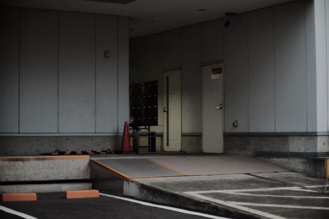 Folding loading ramp bridging a warehouse dock and vehicle