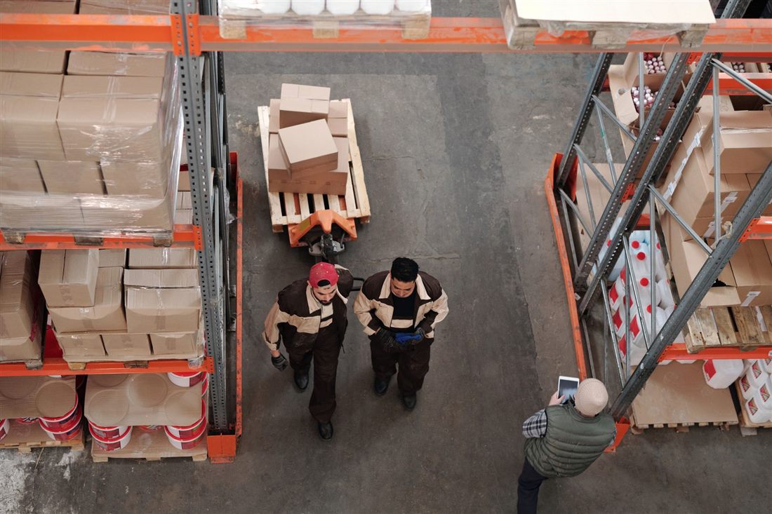 Warehouse staff moving a pallet truck loaded with boxes